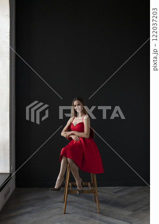 portrait of a beautiful young woman in a red dress, studio shot on a dark background portrait of a beautiful young woman in a red dress, studio shot on a dark background 122037203