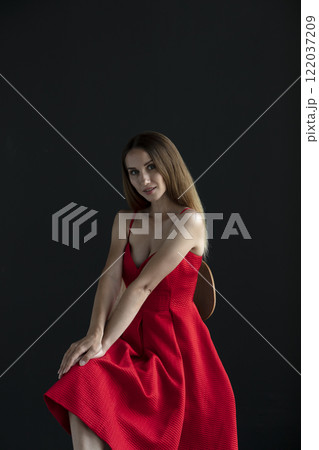 portrait of a beautiful young woman in a red dress, studio shot on a dark background portrait of a beautiful young woman in a red dress, studio shot on a dark background 122037209