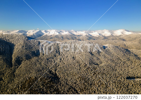 Aerial view of winter landscape with mountain hills covered with evergreen pine forest after heavy snowfall on cold bright day. Aerial view of winter landscape with mountain hills covered with evergreen pine forest after heavy snowfall on cold bright day. 122037270