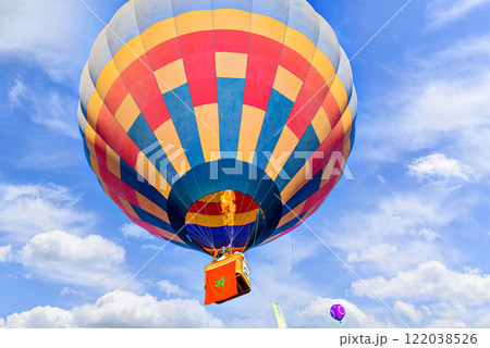 Colorful hot air balloon flying over blue sky with white clouds	 122038526