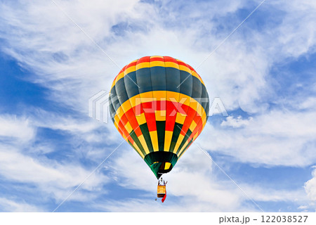 Colorful hot air balloon flying over blue sky with white clouds Colorful hot air balloon flying over blue sky with white clouds 122038527