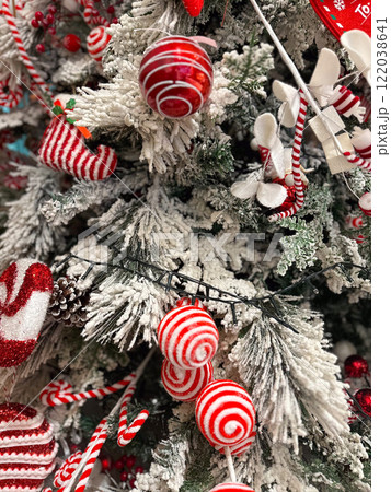 Close-up of a snow dusted Christmas tree with red and white ornaments and baubles. Vibrant festive decorations 122038641