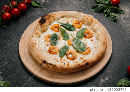 Gourmet shrimp pizza topped with fresh spinach leaves on a golden crust served on a wooden platter 122038763