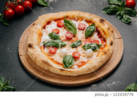 Classic Margherita pizza with cherry tomatoes, mozzarella, and fresh basil on a wooden plate 122038776