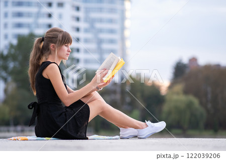 Young woman resting in summer park reading a book. Education and sudy concept. 122039206