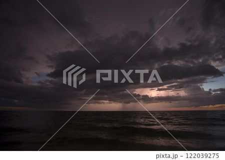 Thunderstorm clouds over rough ocean waters. Evening sea waves crushing on sandy beach. Beautiful seascape at sunset 122039275