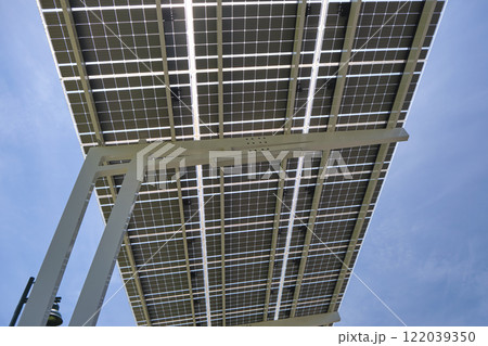 Solar panels installed as shade roof over parking lot for parked electric cars for effective generation of clean electricity. Photovoltaic technology integrated in urban infrastructure 122039350