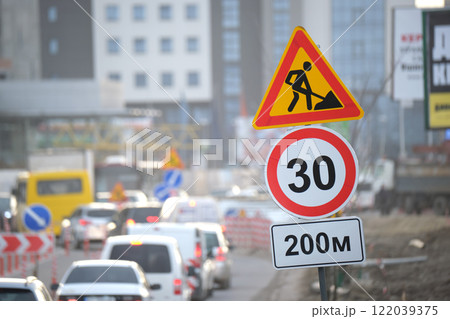 Roadworks warning traffic signs of construction work on city street and slowly moving cars 122039375