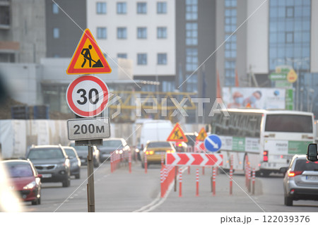 Roadworks warning traffic signs of construction work on city street and slowly moving cars 122039376
