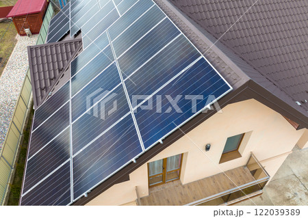 Residential house with rooftop covered with solar photovoltaic panels for producing of clean ecological electrical energy in suburban rural area. Concept of autonomous home Residential house with rooftop covered with solar photovoltaic panels for producing of clean ecological electrical energy in suburban rural area. Concept of autonomous home 122039389