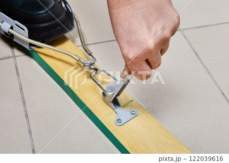 Adjusting tension lever of spring cable ski binding during installation on wooden skis. 122039616