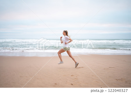 Determined sporty woman running on seashore at 122040327