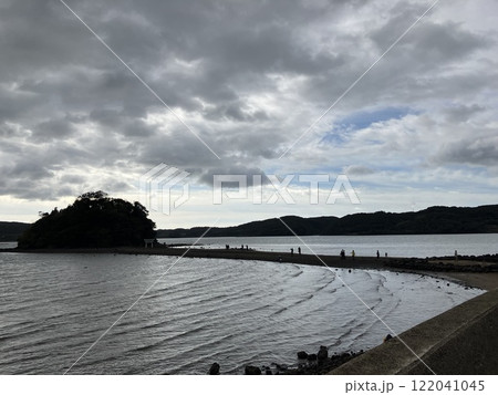 干潮で海の中にできた道を歩く人々 122041045