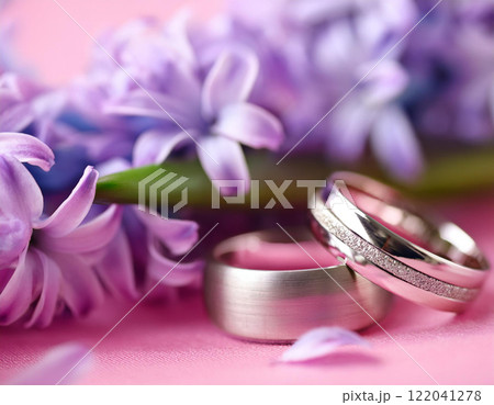 AI generative image of two titanium and diamond wedding rings on pink background with hyacinth. Shallow depth of field, close up the wedding ring with space. 122041278