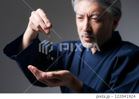 緑茶の茶葉を見る作務衣の男性 122041924