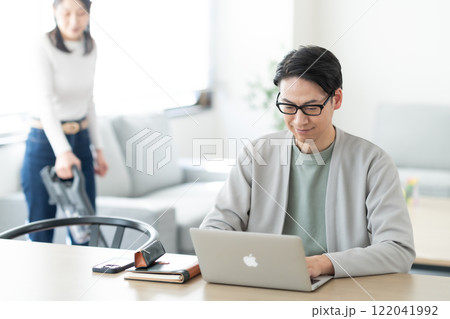 自宅でテレワークする夫と家事をする主婦 122041992