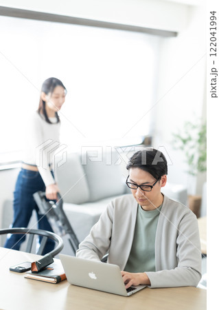 自宅でテレワークする夫と家事をする主婦 自宅でテレワークする夫と家事をする主婦 122041994