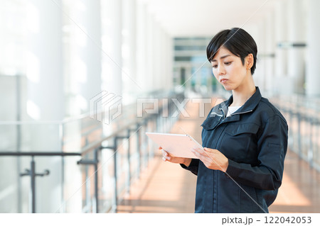 オフィスでタブレットを使う作業服の女性 122042053