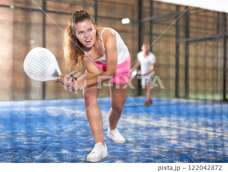 Young beautiful woman with racket playing padel 122042872