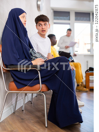Guy talking to asian woman sitting in lobby of medical clinic 122042875