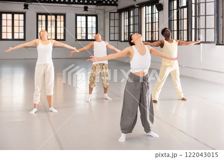 Men and women perform yoga dance in dance hall 122043015