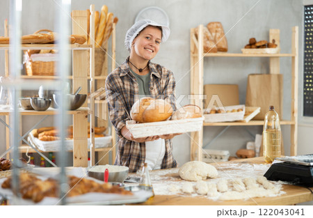 Bakery woman employee holds ready made bread of bread 122043041