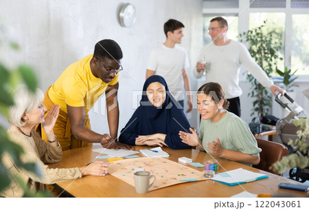 Cheerful african american man playing board game with friends Cheerful african american man playing board game with friends 122043061