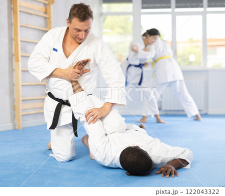 Cosmopolite sportsmen train of performing protection with wring hands during training in aikido 122043322