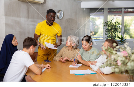Experienced male coach conducts training for people of different nationalities in classroom 122043324