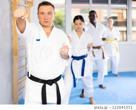 Multinational students repeat position and perform sequence of punches and painful techniques kata Multinational students repeat position and perform sequence of punches and painful techniques kata 122043351