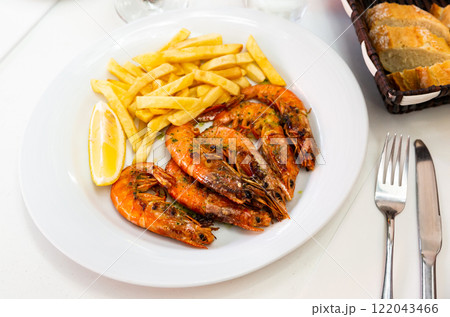 Appetizing baked shrimps with lemon and french fries Appetizing baked shrimps with lemon and french fries 122043466