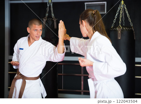 Man and woman in pairs exercising karate movements during group training in gym Man and woman in pairs exercising karate movements during group training in gym 122043504