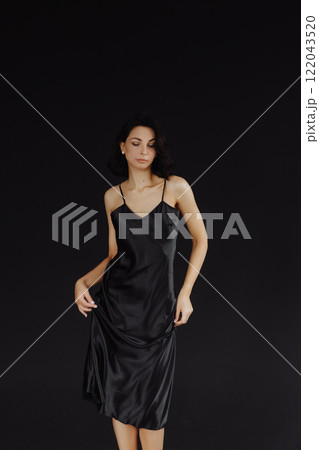 Young woman in black dress standing on black background Young woman in black dress standing on black background 122043520