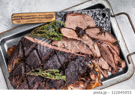 Roasted game meat of Venison, baked leg of roe deer on a tray with herbs. white background. top view 122045055