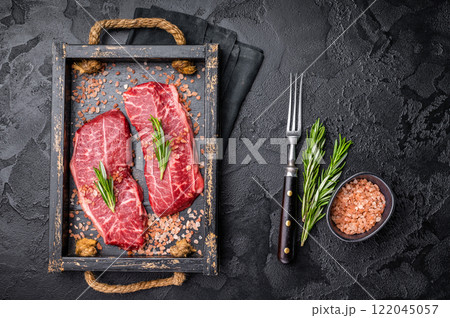 Raw Top blade steak, shoulder beef meat in wooden tray. black background. top view Raw Top blade steak, shoulder beef meat in wooden tray. black background. top view 122045057