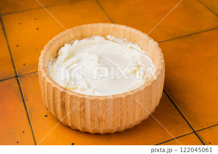 Cream texture, Mascarpone Italian cream cheese in wooden bowl. orange background. top view Cream texture, Mascarpone Italian cream cheese in wooden bowl. orange background. top view 122045061