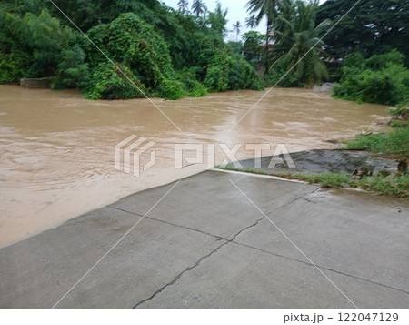Brown water flood flowing and flooding concrete road until cars can't travel 122047129