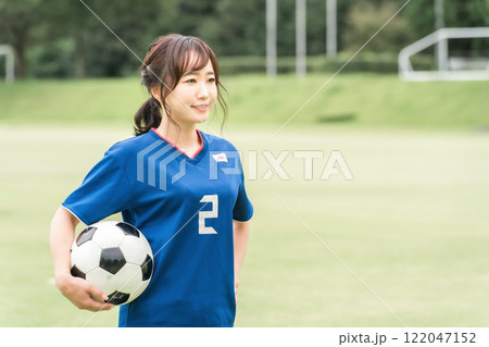 サッカーボールを持ちながら笑顔でサッカーするファン・サポーターの日本人女性 122047152