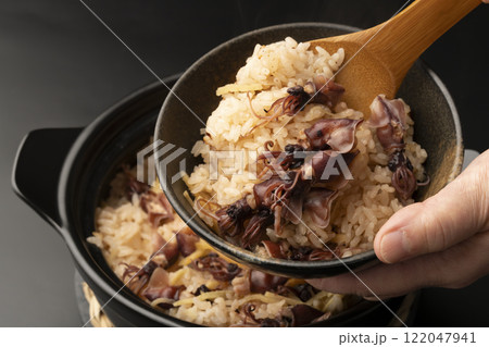 土鍋で炊いたホタルイカの炊き込みご飯を茶碗に盛り付ける  122047941
