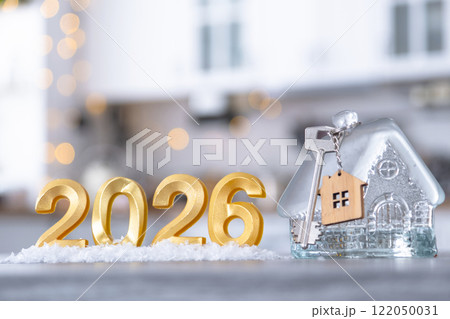 Golden number 2026, key and tiny home on background of cozy white kitchen with Christmas tree and Christmas decor with garland lights. Housing, interior, renovation, mortgage, rent in New Year Golden number 2026, key and tiny home on background of cozy white kitchen with Christmas tree and Christmas decor with garland lights. Housing, interior, renovation, mortgage, rent in New Year 122050031