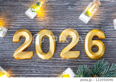 Happy New Year golden numbers 2026 on cozy festive grey wooden background with Christmas tree, snow, lights of garlands. Greetings, postcard. Calendar, cover 122050046