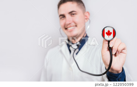 Smiling doctor showing stethoscope with Canada flag. Canada National Healthcare concept 122050399