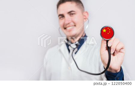 Smiling doctor showing stethoscope with China flag. China National Healthcare concept 122050400