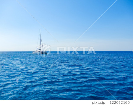 Sailboat drifting on calm blue ocean under clear sky, peaceful and serene scene. High quality photo 122052160
