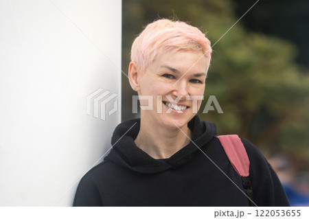 Cheerful middle-aged woman with short hair and a black jacket outdoors Cheerful middle-aged woman with short hair and a black jacket outdoors 122053655