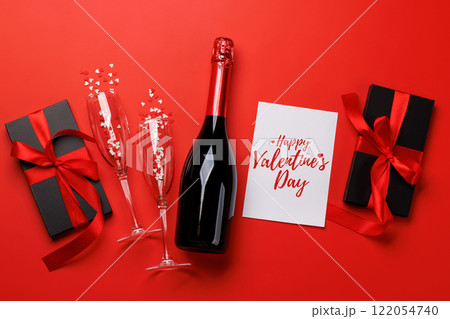 Champagne and gift: Celebratory duo on a red background with text space Champagne and gift: Celebratory duo on a red background with text space 122054740