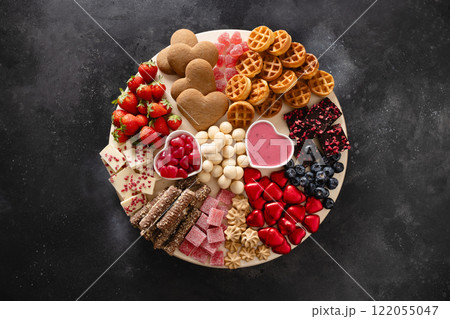 Valentines Day charcuterie board with chocolate, different candy sweets, strawberries, blueberries on black background. View from above. Valentines Day charcuterie board with chocolate, different candy sweets, strawberries, blueberries on black background. View from above. 122055047