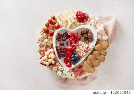 Charcuterie Valentines Day sweet board with chocolate candy, red hearts, cookies, marshmallow, strawberries and candies on white background. Copy space. Top view. 122055048