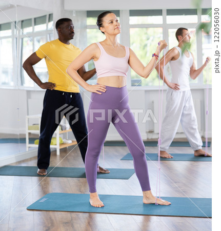 Group of sporty people stretch their arms and legs using an expander 122056030