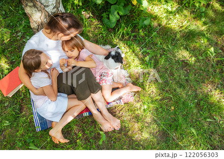Family sharing a loving embrace under a tree on a sunny day 122056303